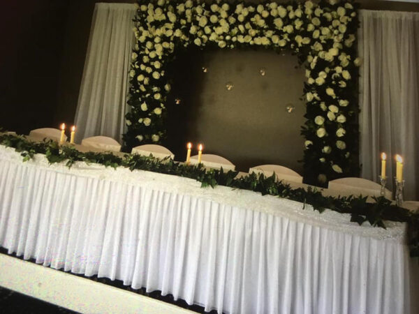 White floral and greenery arch with drapery
